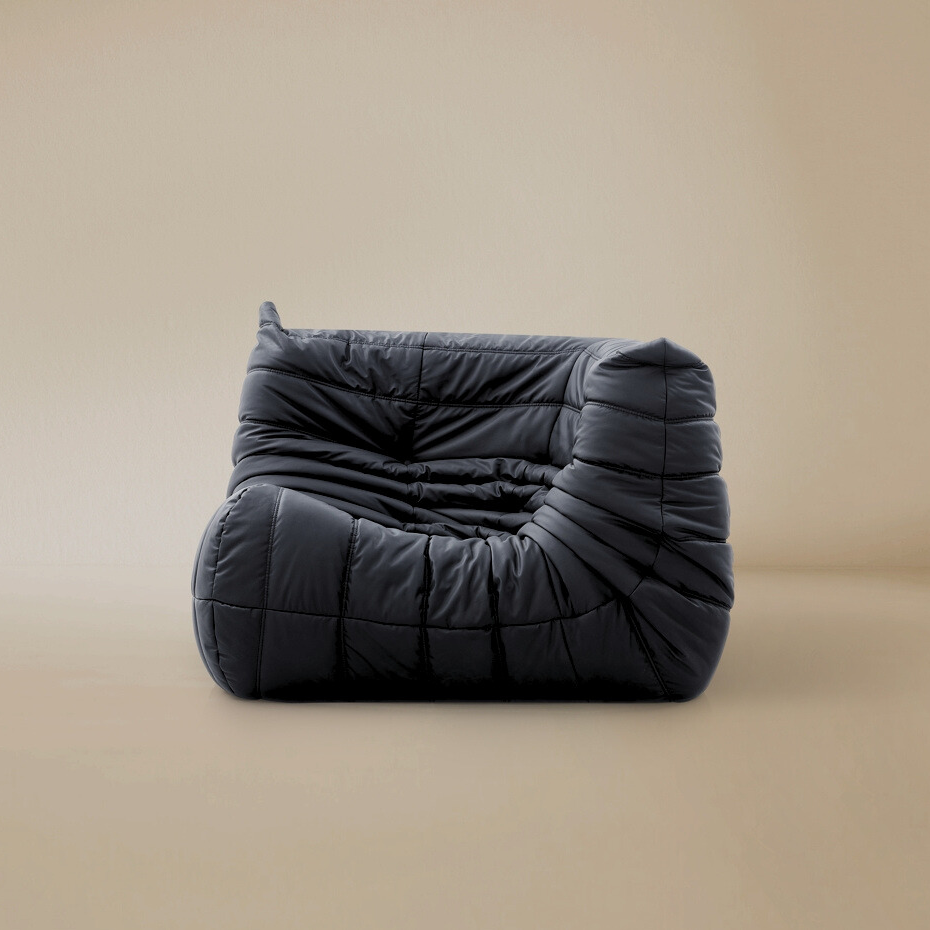 Side angle view of the TOGO corner seat in dark grey showing the curved back support and pleated upholstery.