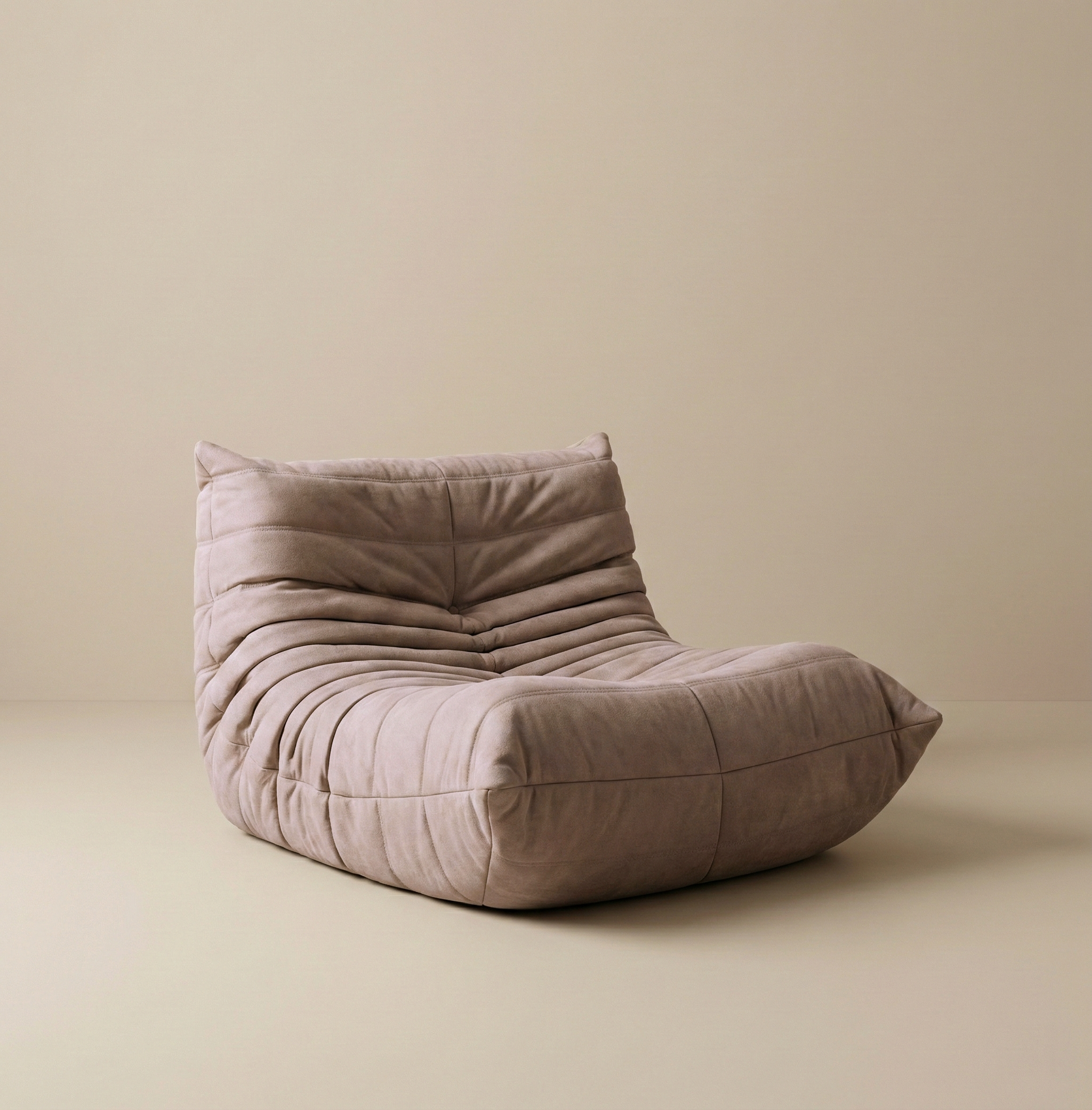 TOGO Lounger single seater in neutral taupe suede showing soft pleated texture and ergonomic shape.