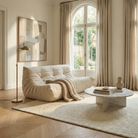 Modern living room with a beige sofa, round coffee table, and large window.
