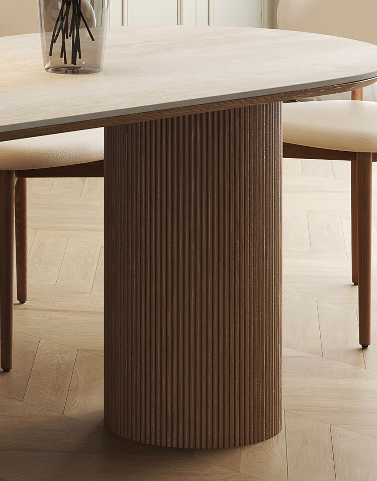 Close-up of travertine sintered stone dining table with fluted solid wood base on light oak floor