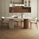 Travertine sintered stone dining table with wood base styled with cream chairs in modern kitchen interior