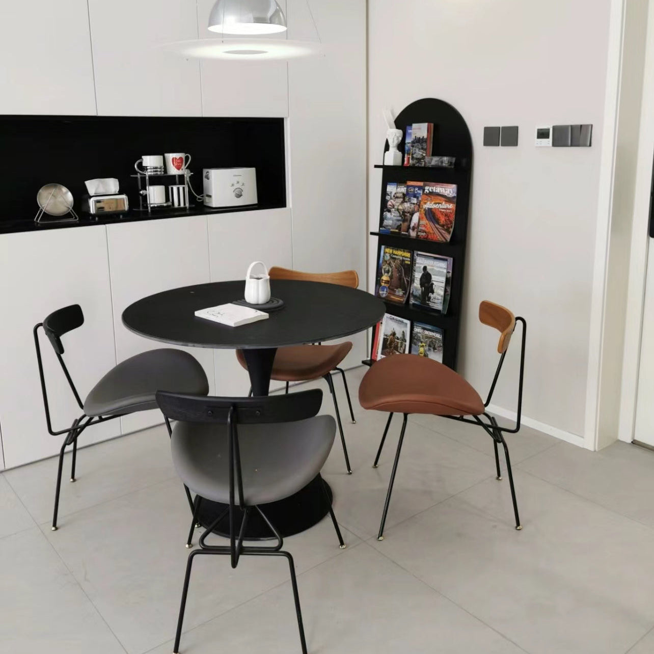 Black Tulip Dining Table styled in a modern kitchen nook with minimalist chairs and magazine rack decor