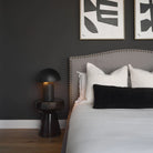 Umbra black dome lamp styled on a black side table in a moody modern bedroom with a grey upholstered bed.