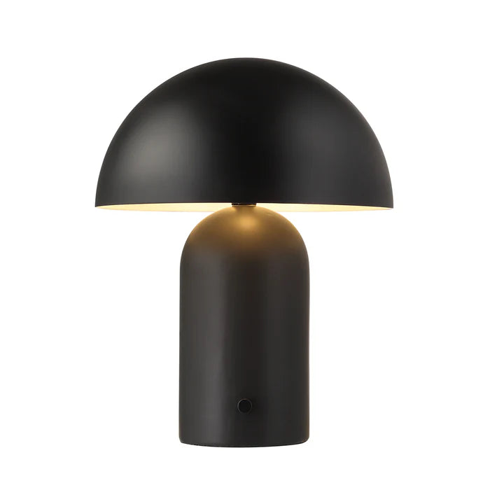 Lit view of the Umbra black metal table lamp casting a warm downward glow from its dome shade.