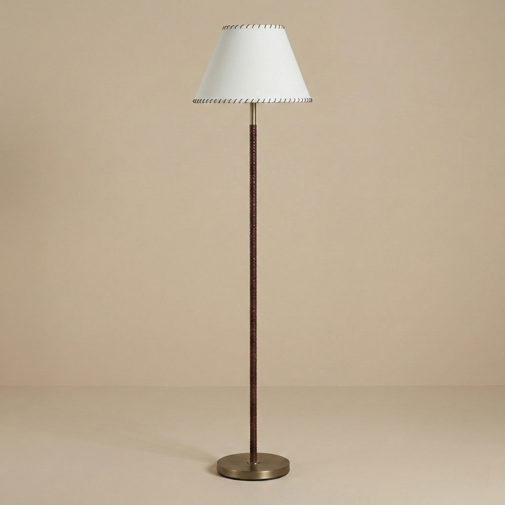 Valen floor lamp featuring a slender stem wrapped in cognac leather with contrast stitching and a white linen shade.