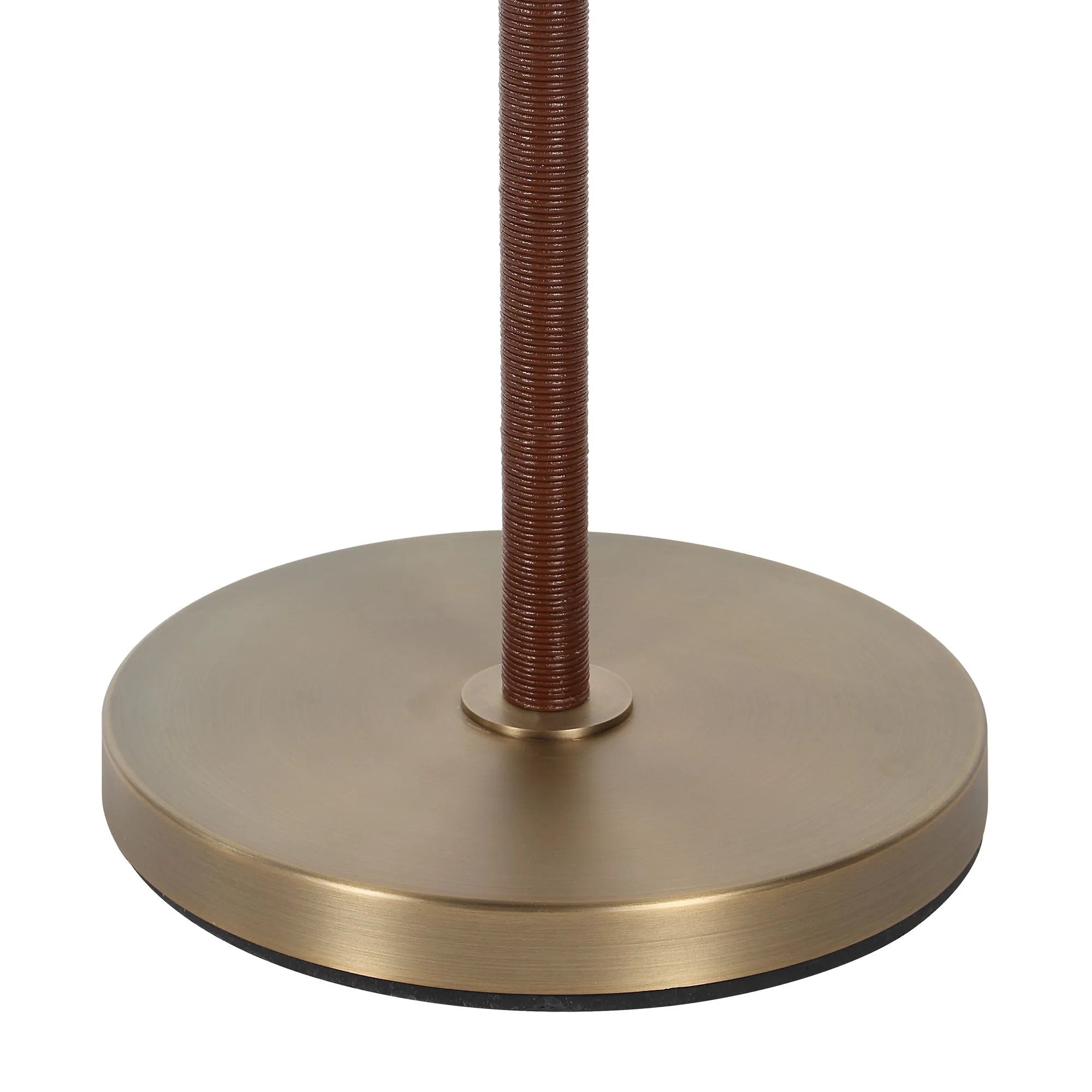 Close up detail of the Valen lamp's round brushed brass base and textured brown leather wrapped pole.