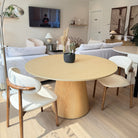 Willow Ridge round dining table in solid ash wood with cream chairs displayed in cozy showroom