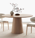 Close-up of Willow Ridge round dining table in solid ash wood with cream chairs and vase decor