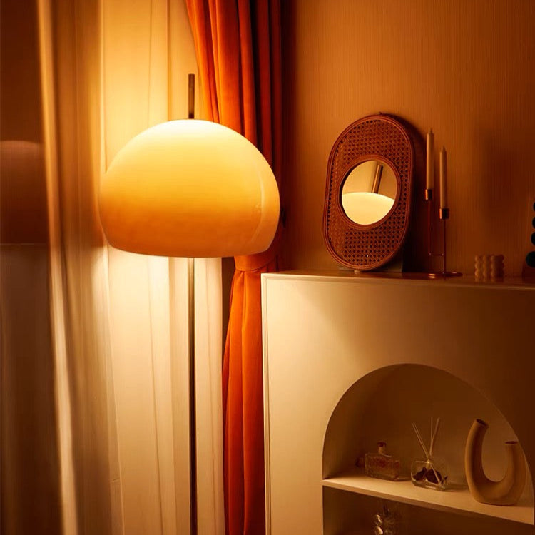 Yellow Dome Glass Standing Floor Lamp casting soft amber light beside white shelf and orange curtain